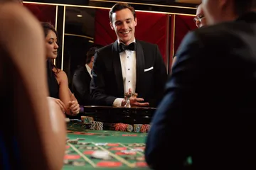 A professional dealer in a tuxedo greeting players at the roulette table, symbolizing the authentic live casino feel at DBJL.